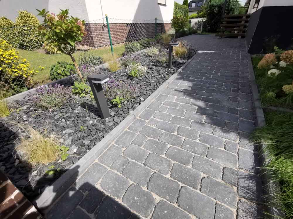 Gepflasterter Weg mit Steinbeet und Bepflanzung